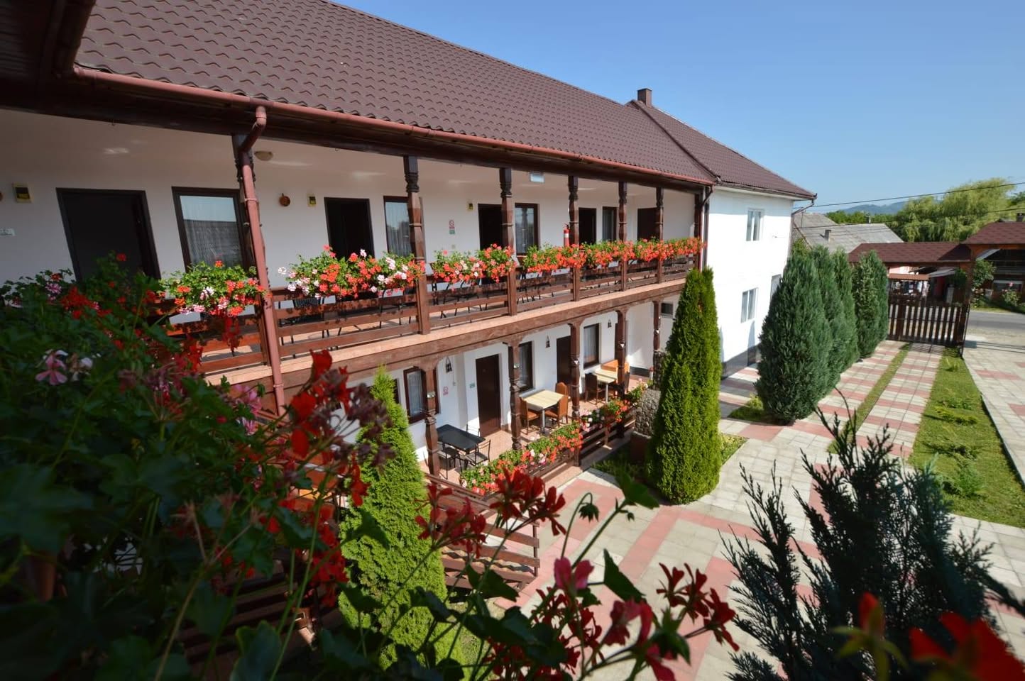 Terasă exterioară cu balcoane de lemn și geranium roșu
